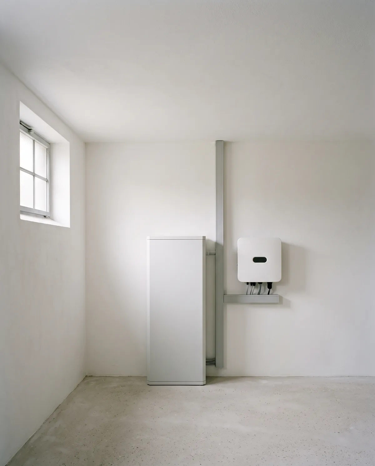Heller Technikraum mit weißem Batteriespeicher und Wechselrichter an der Wand